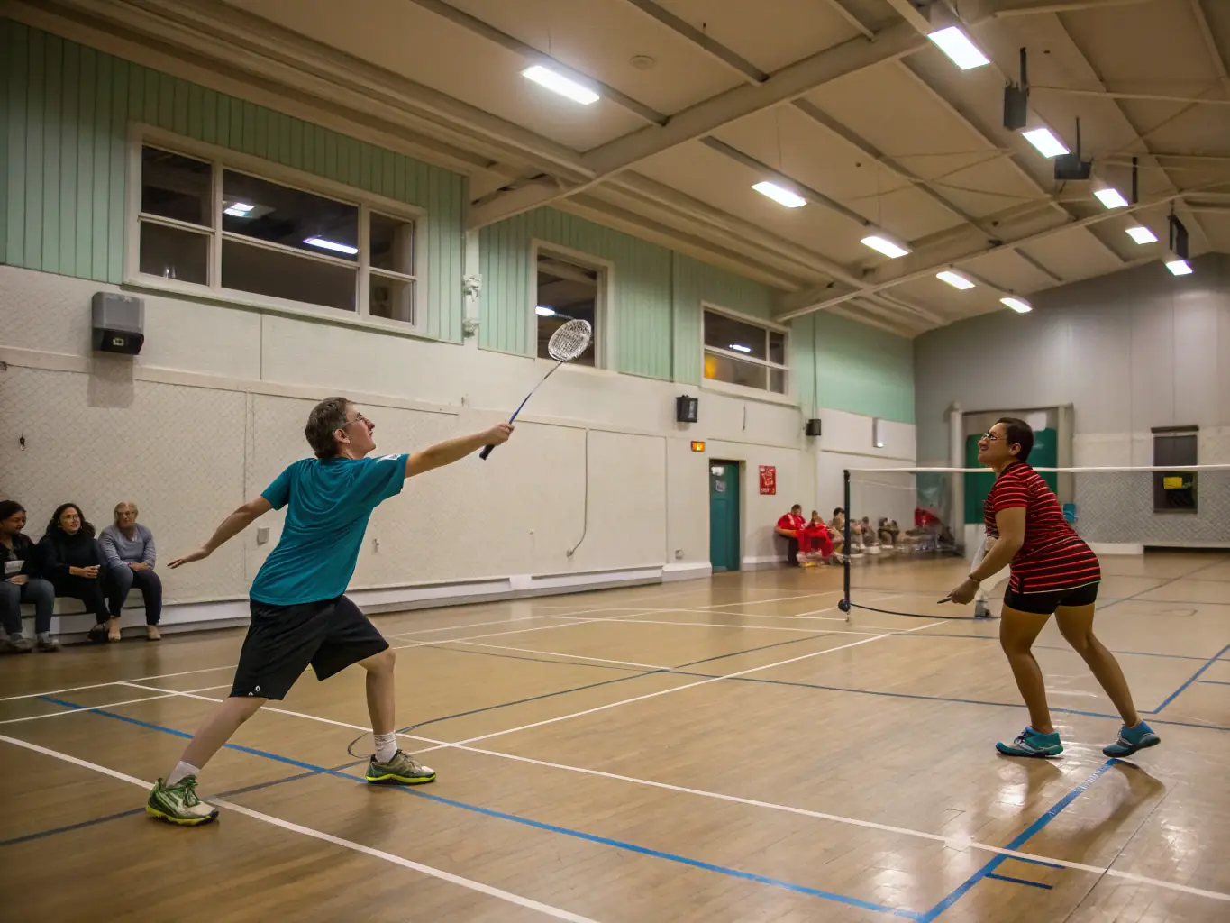 A diverse group of adults playing badminton in a well-lit indoor court, highlighting the inclusive and social aspect of LA RAQUETTE CHAMPAGNACOISE's adult programs.