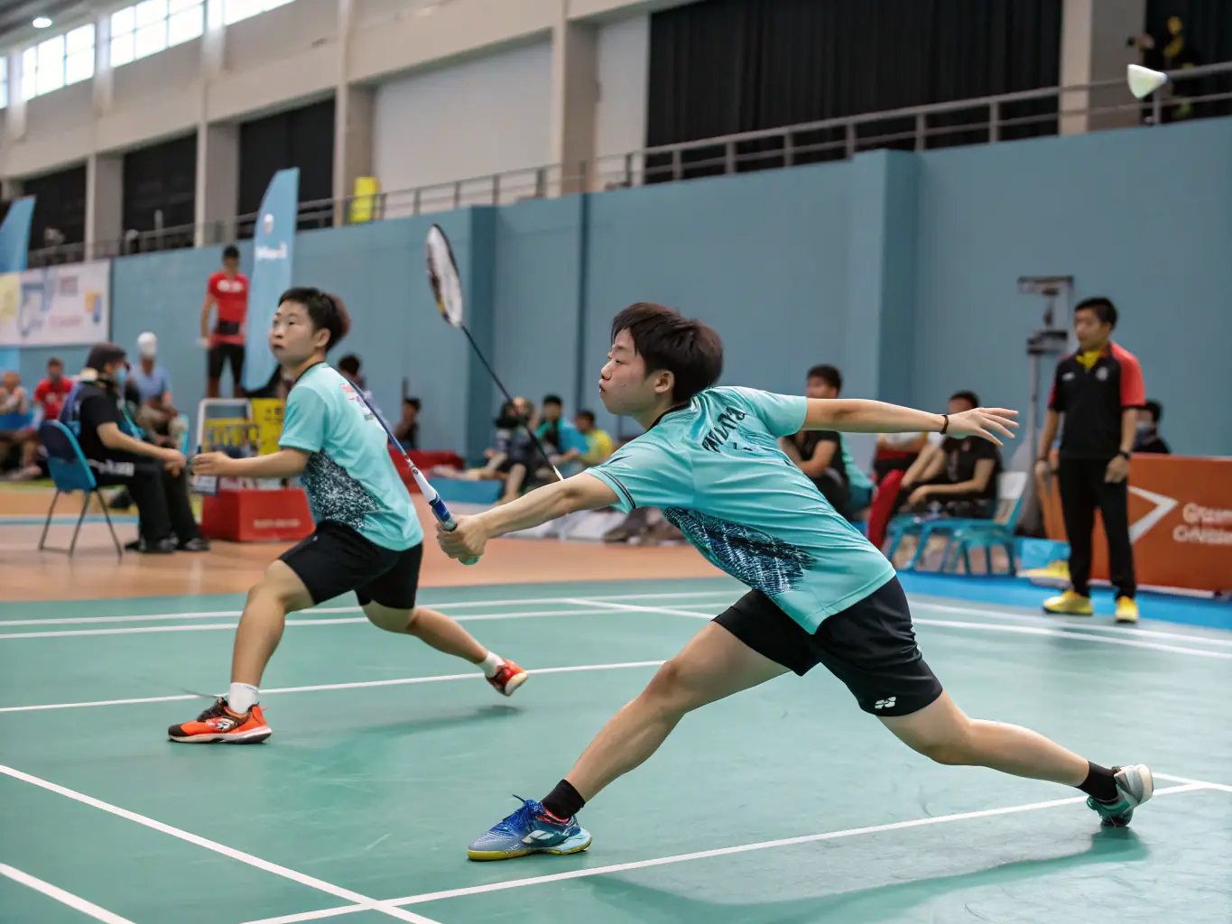 An action shot of badminton players in mid-air, hitting shuttlecocks during a fast-paced game in an indoor court at LA RAQUETTE CHAMPAGNACOISE.